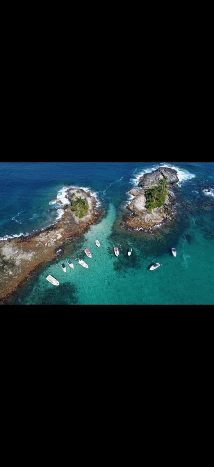 Vista aérea de ilhotas rochosas cercadas por mar azul e embarcações